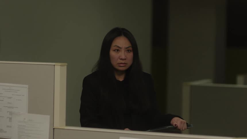 An asian woman looks sad in an office