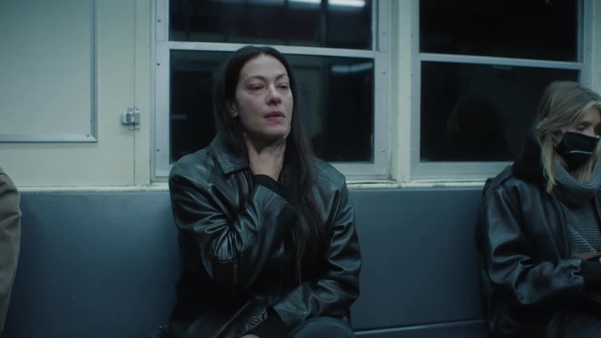 Woman sitting on the seat of a moving train wiping her face with tears of tears