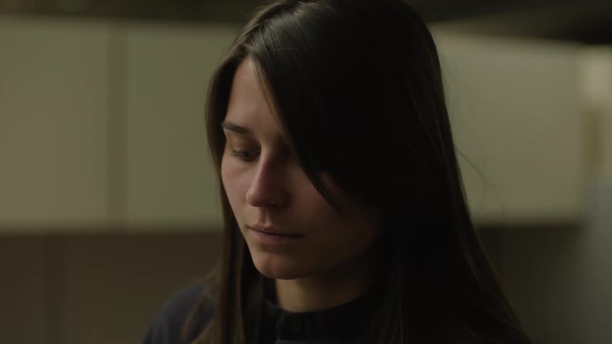 A young sad woman with long hair looks down