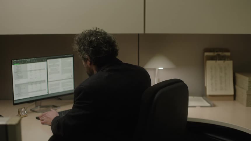 A man is typing on his computer in his office
