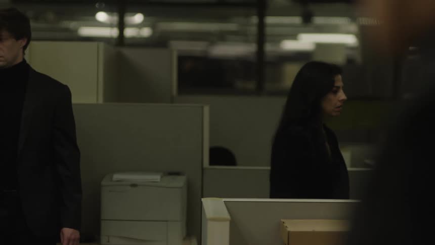Man and woman standing in office aisle at night turn and walk away from each other