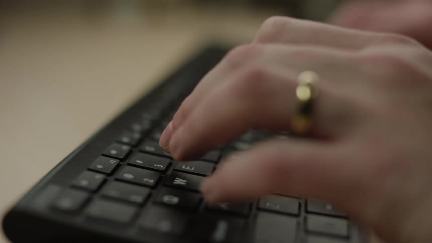 A closeup of a persons hands typing on a computer laptop