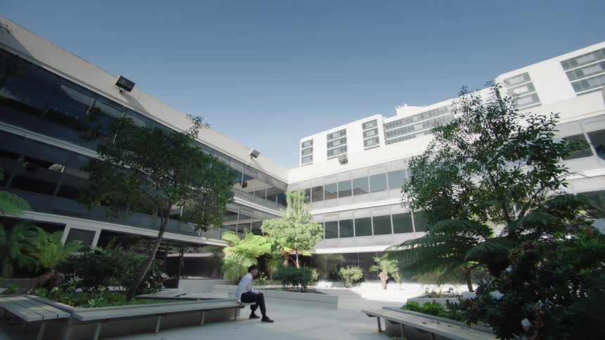 A worker sits in the courtyard in front of the office building
