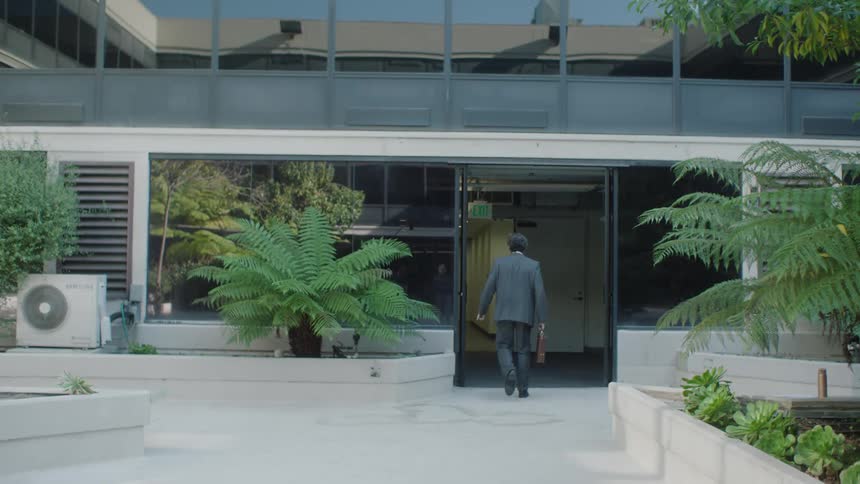 A man in a suit and briefcase is walking into an establishment