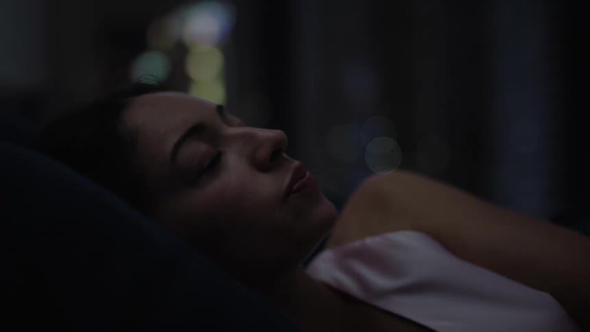 A woman tosses about while sleeping in a bed
