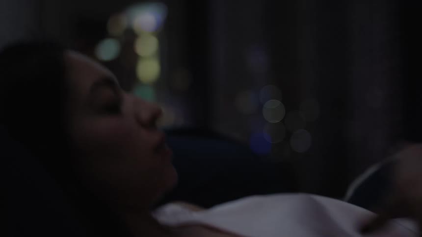 Woman lying down and adjusting herself in bed