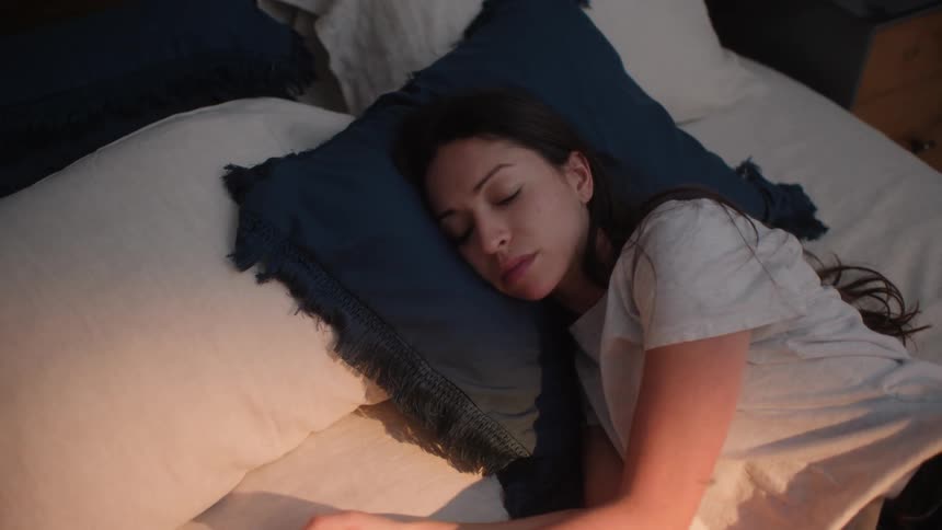 A sad young woman tosses in bed