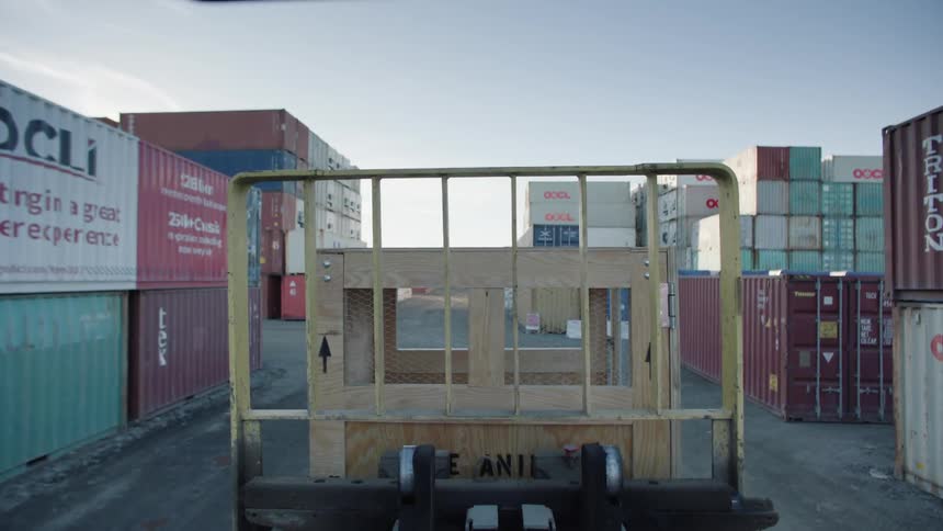 A truck driving around a shipping yard full of containers