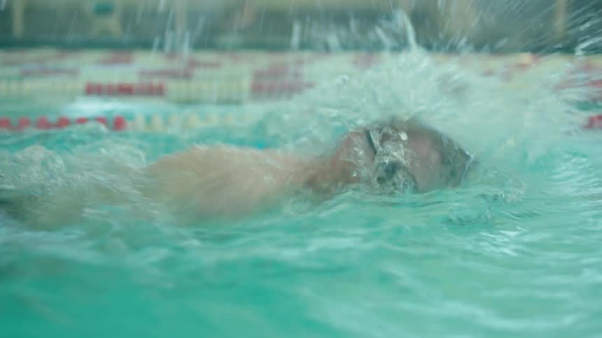 A man freestyle swimming and wearing googles in a pool