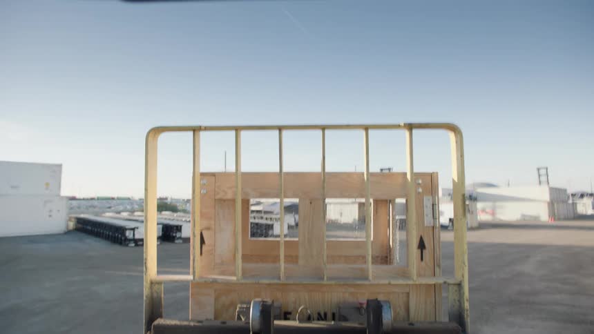 A forklift driving across lanes of shipping containers