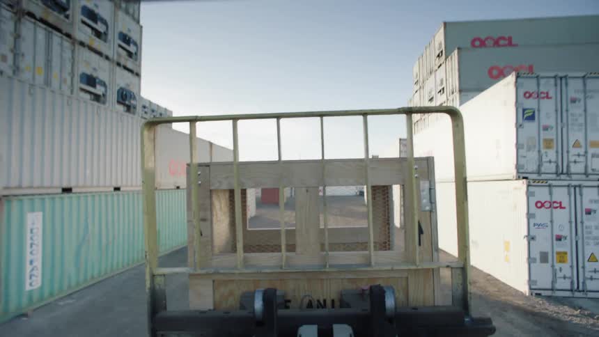 A forklift driving across lanes of shipping containers