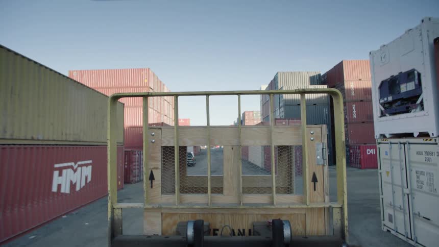 A vehicle carrying a wooden box in a place full of containers