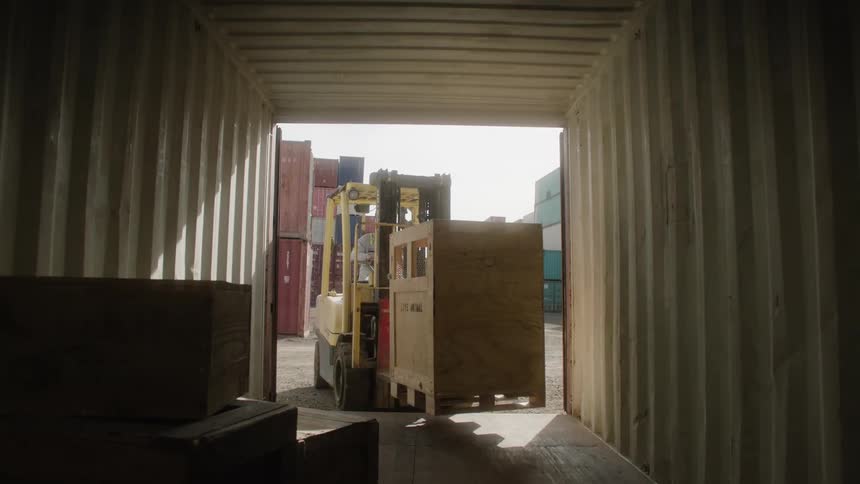 A man in a forklift removes a case from a storage container