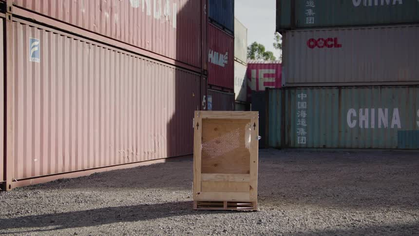 Wooden box open on the front in an outdoor environment with containers around