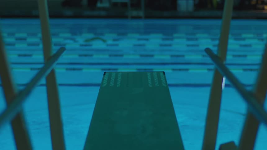 Legs of a woman jumping towards a illuminated pool at night