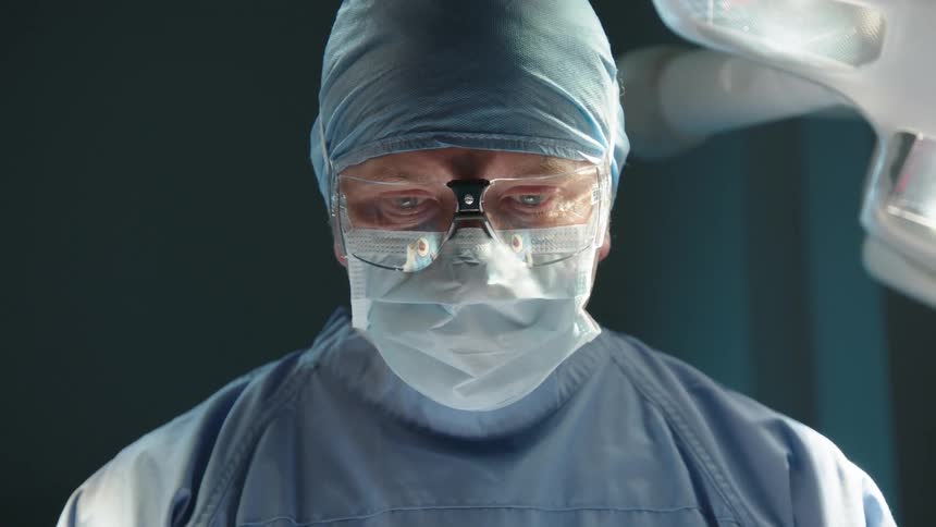 Portrait of a surgeon doctor with a concentrated look and wearing specific clothing while in a surgical environment