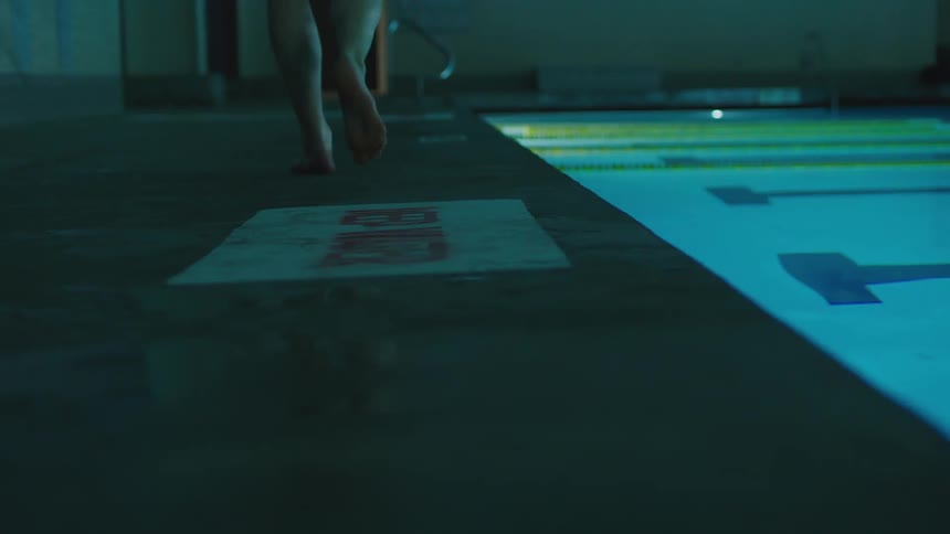 Legs of a person standing in front of a swimming pool and then running out of the area