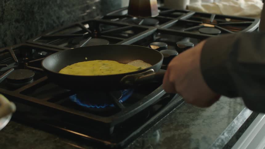 A person is cooking eggs on the pan
