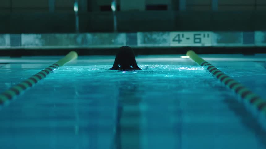 In a pool a woman swims alone to the side and holds onto it