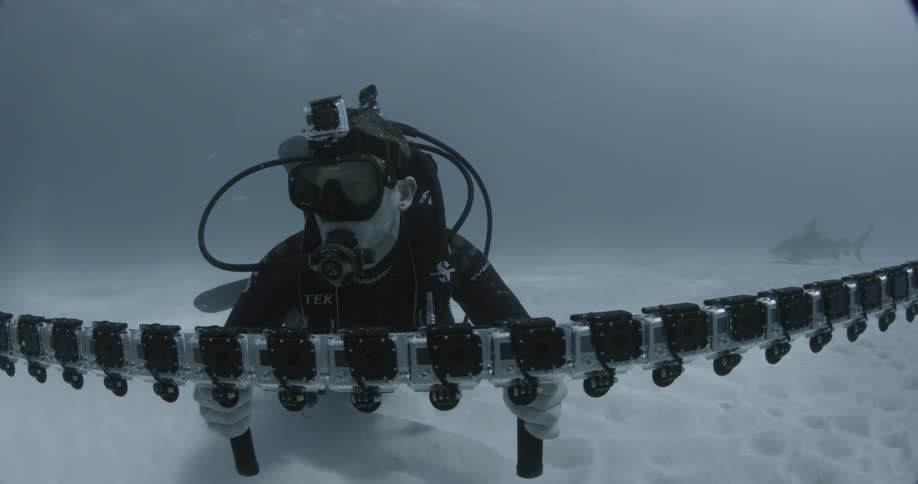 A diver is holding a bar of cameras filming sharks underwater