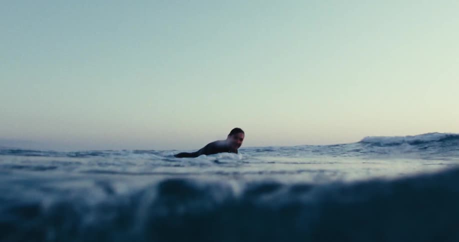 A surfer in a sea with an approaching wave