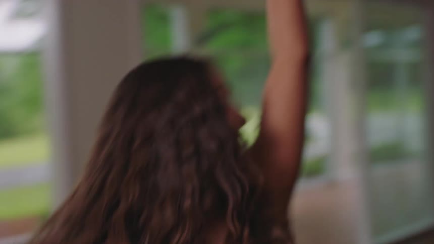 Portrait of a smiling young woman dancing and throwing her arms back