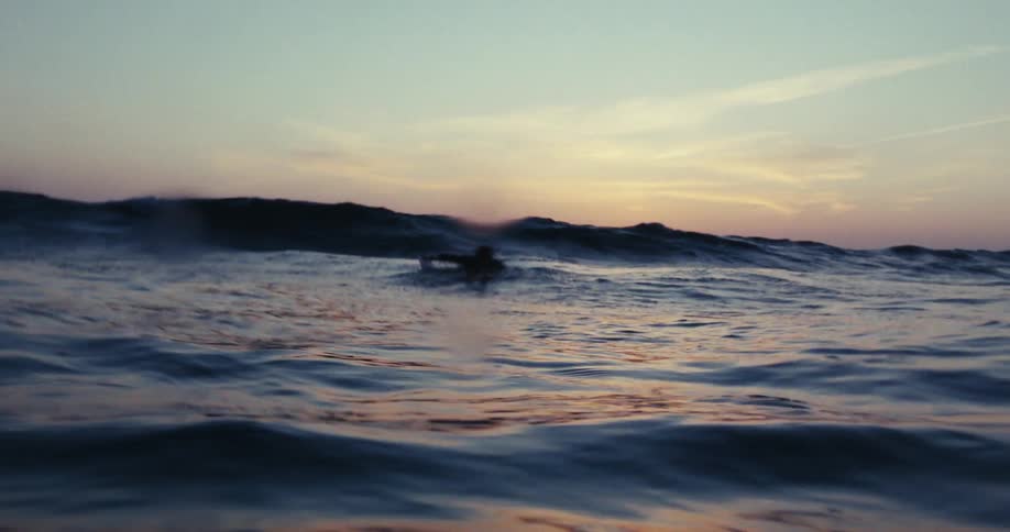A man is paddling into the ocean
