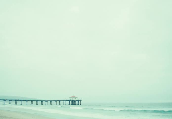 A beach with a long pier with and without a lens filter