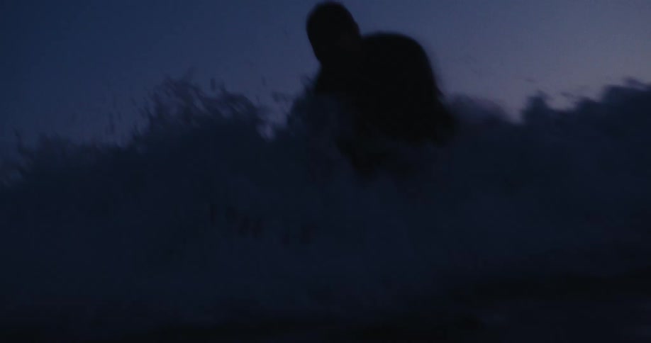 A silhouette of a person surfing a wave at sea