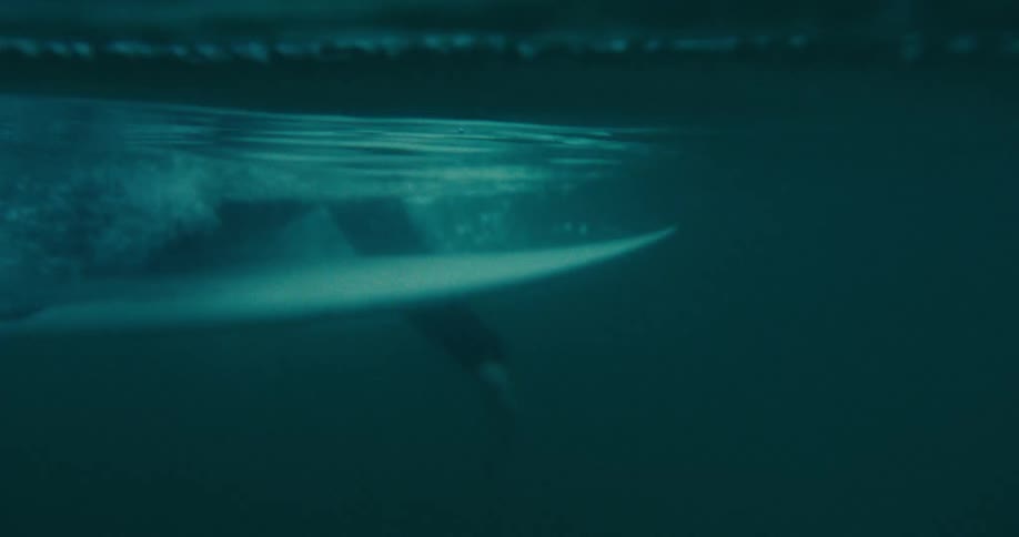 Underwater footage of a surfer swimming over a surfboard