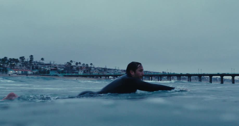 A surfer swimming in the sea while lying on his board