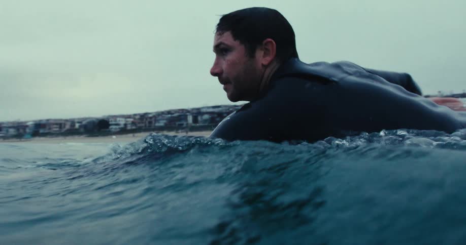 Man in the ocean swimming with his surfboard