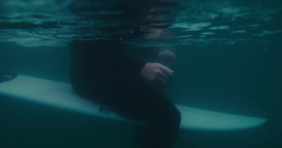 Underwater shot of a surfer straddling a surfboard in the ocean