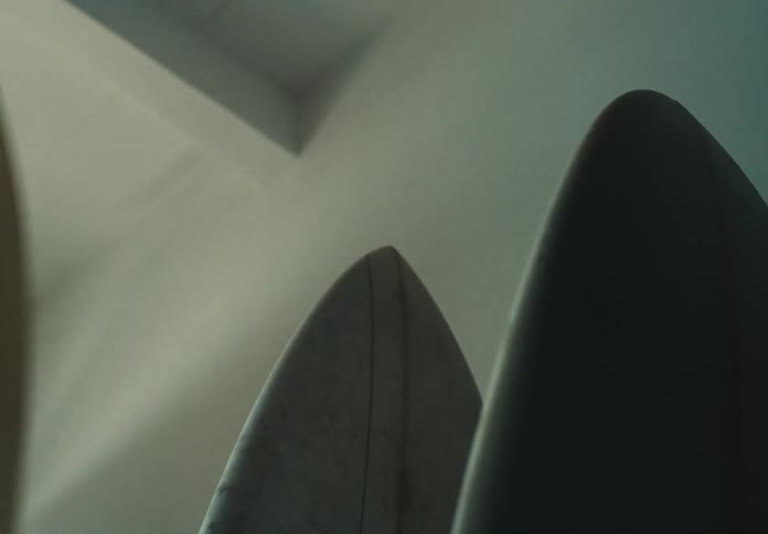 Person walking into a dark room and grabbing a surboard from the wall