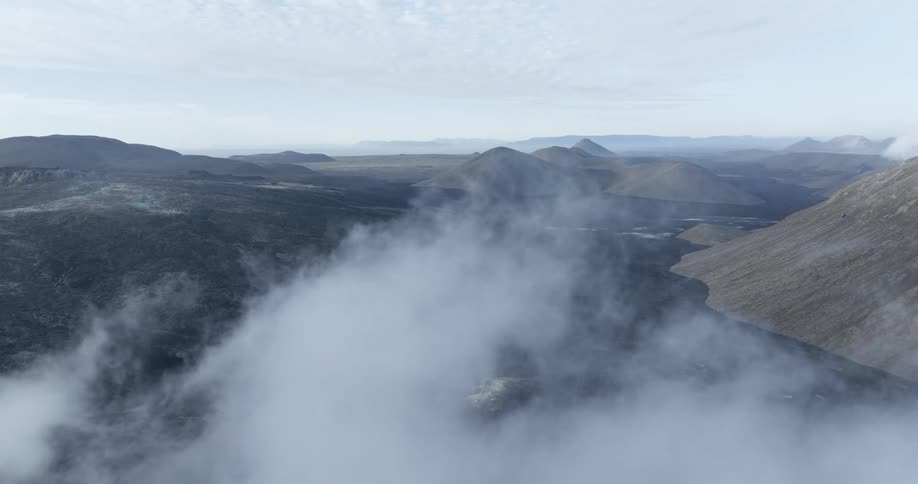 Aerial view of a volcanic landscape behind columns of smoke