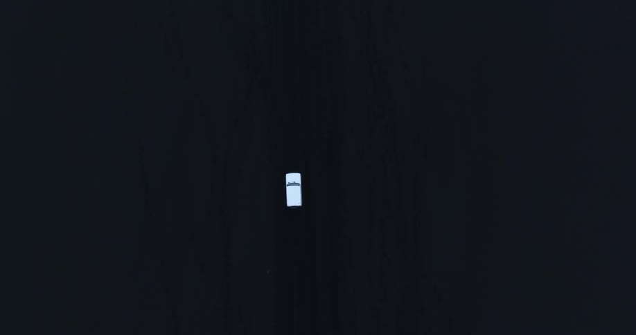 Top view of a white car traveling on black natural soil