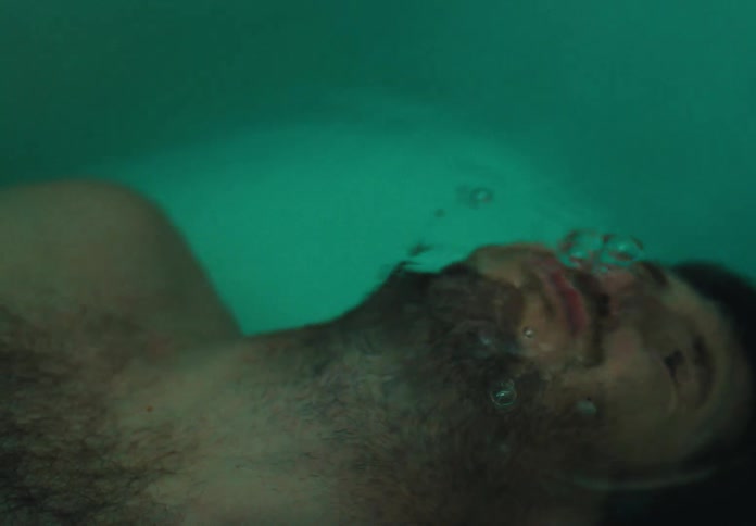 Close up of a man submerging his head on a bathtub