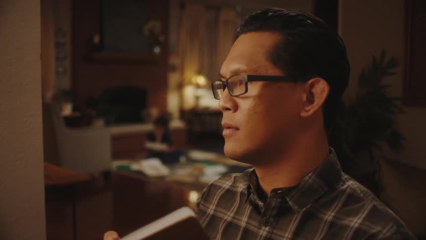 Father writing in a book and in the background his son playing in the living room