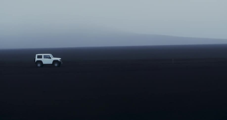 White jeep vehicle traveling on black ground on a foggy day