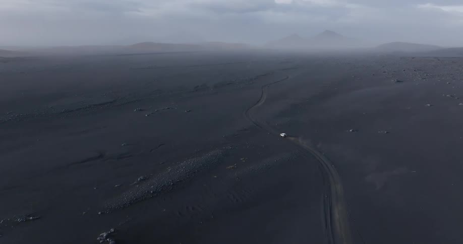 A vehicle drives across a vast lava field