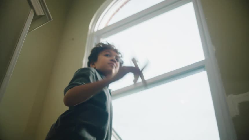 Boy climbing the stairs at home and then throwing a toy plane into the air