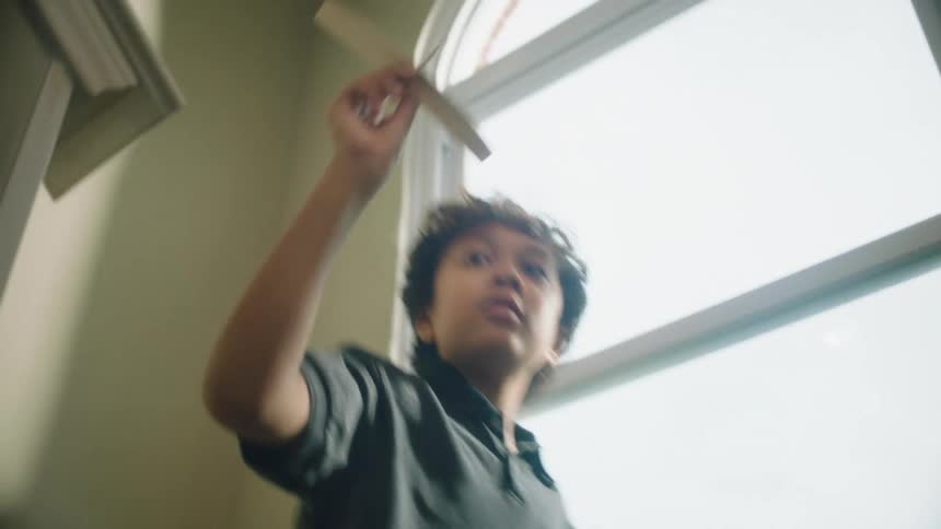 Boy runs up staircase with a toy plane and throws it into the air