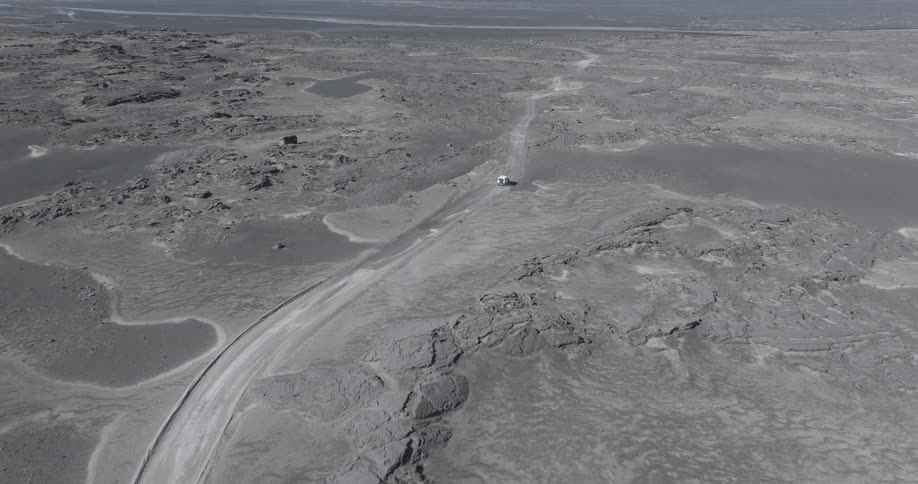 Aerial panorama of a white vehicle traveling in a natural environment with grayish ground