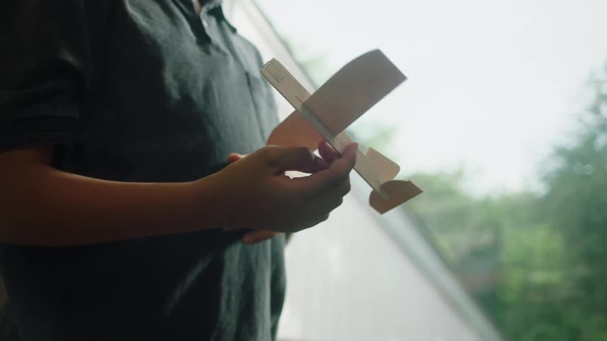 Boys hand holding a small plane made of cardboard