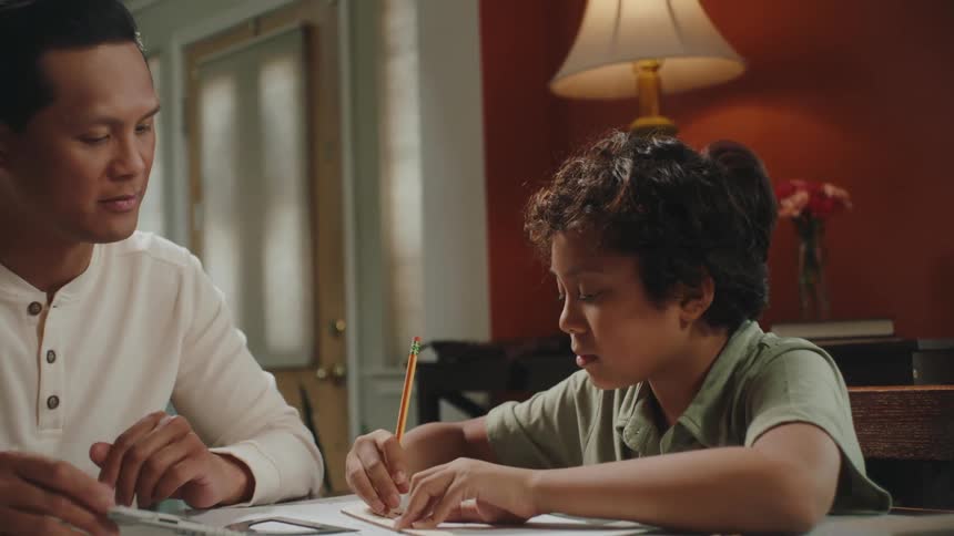 Father helping his son with homework in the living room