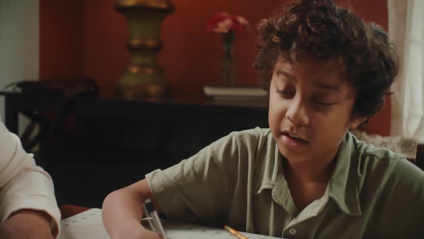Father sitting with his son at the table with books studying