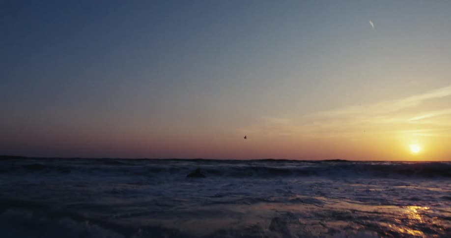 A surfer swimming on the ocean at sunset