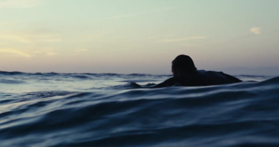 Surfer paddling in the ocean at dawn
