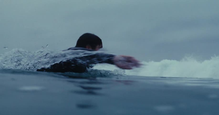A man swims off of a coast