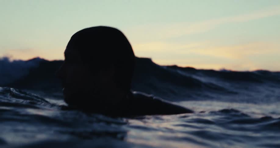Silhouette of the head of a man swimming in the ocean at dusk